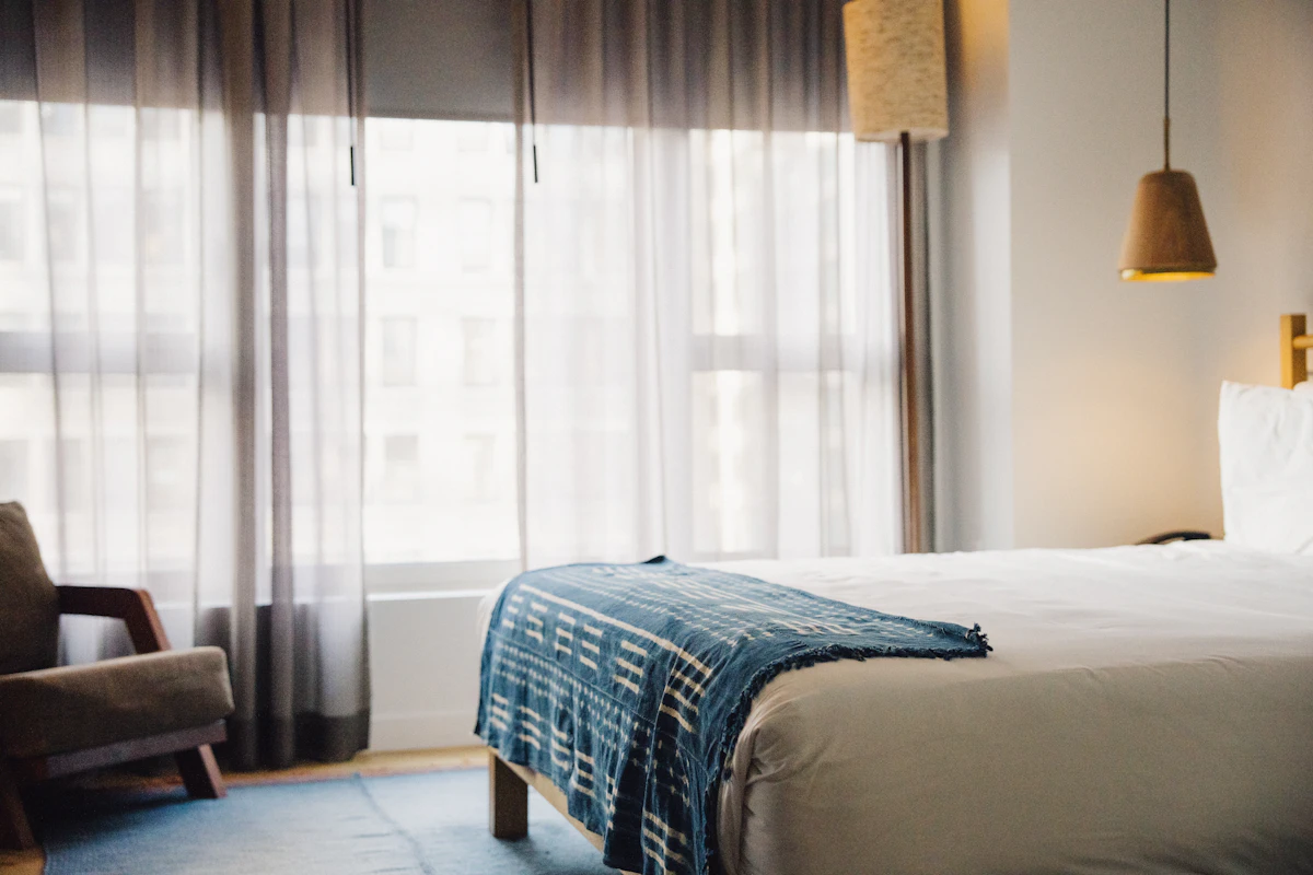 Hotel guest room with a neatly made bed and a large window