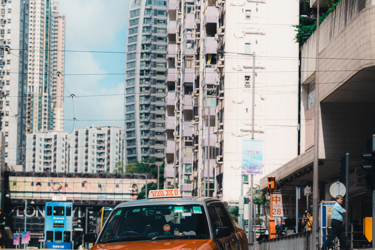 Orange city taxi travelling through a high-rise district
